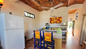 Una cucina con frigorifero, ventilatore a soffitto e zona pranzo con sedie.