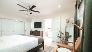 A bedroom with a bed, a ceiling fan, a TV, a desk, and a chair. - Luxury Villa Miami Shores (Miami Shores)