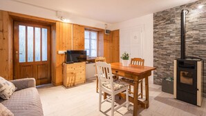 A cozy room with a wooden dining table, chairs, a TV, and a fireplace. - Stunning private villa for 4 guests with WIFI, TV, patio and pets allowed (Armeno)