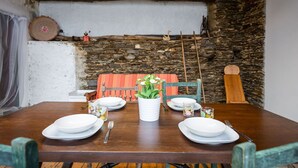 A rustic dining area with a wooden table set for four, stone walls, and a traditional wooden chair. - Stunning private villa for 4 guests with WIFI, TV, patio and pets allowed (Armeno)