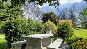 A stone picnic table with benches in a garden with mountains in the background. - Lovely apartment for 5 people with WIFI, TV, patio and pets allowed (Samolaco)