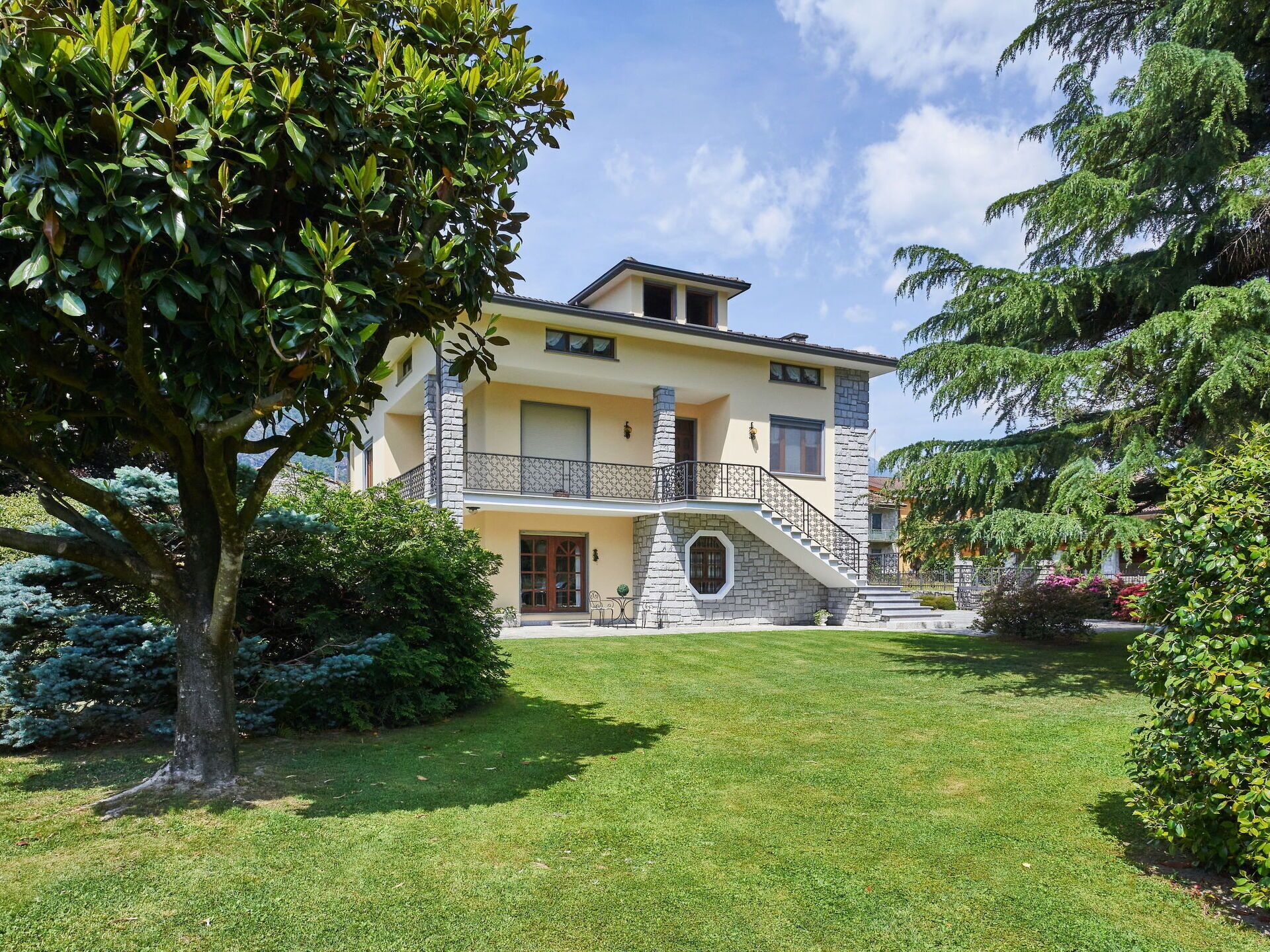Une maison à deux étages avec un escalier en pierre menant à un balcon.