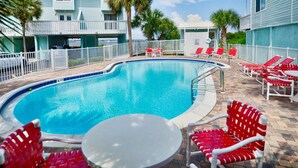A swimming pool with red and white lounge chairs, a small table, and a white fence surrounding the area. - Newly Renovated Home away from Home...Sandcastle Beach #43 (Navarre)