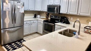 A kitchen with white cabinets, stainless steel appliances, a microwave, an oven, and a sink. - Newly Renovated Home away from Home...Sandcastle Beach #43 (Navarre)