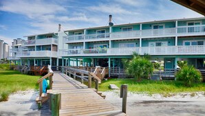A multi-story hotel with balconies and a wooden boardwalk leading to the entrance. - Newly Renovated Home away from Home...Sandcastle Beach #43 (Navarre)
