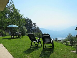 Un área de estar al aire libre con césped, dos sillas y una mesa, con vistas a un paisaje montañoso.