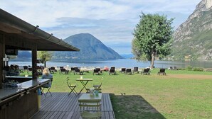 Une terrasse avec des sièges extérieurs, un bar et une vue sur un lac et des montagnes.