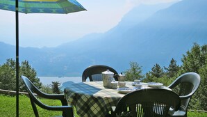 Une table dressée à l’extérieur, avec vue sur les montagnes et un lac.