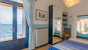 A bedroom with a bed, a window with curtains, a radiator, and a view of the sea. - Nice apartment for 3 people with WIFI and TV (Rezzonico)
