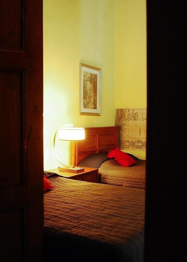 Hotelkamer met een bed, nachtkastje met lamp, een ingelijst schilderij aan de muur en een gestreept hoofdeinde.
