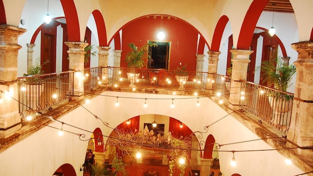 Un atrio de varios niveles con arcos rojos y una escalera central.