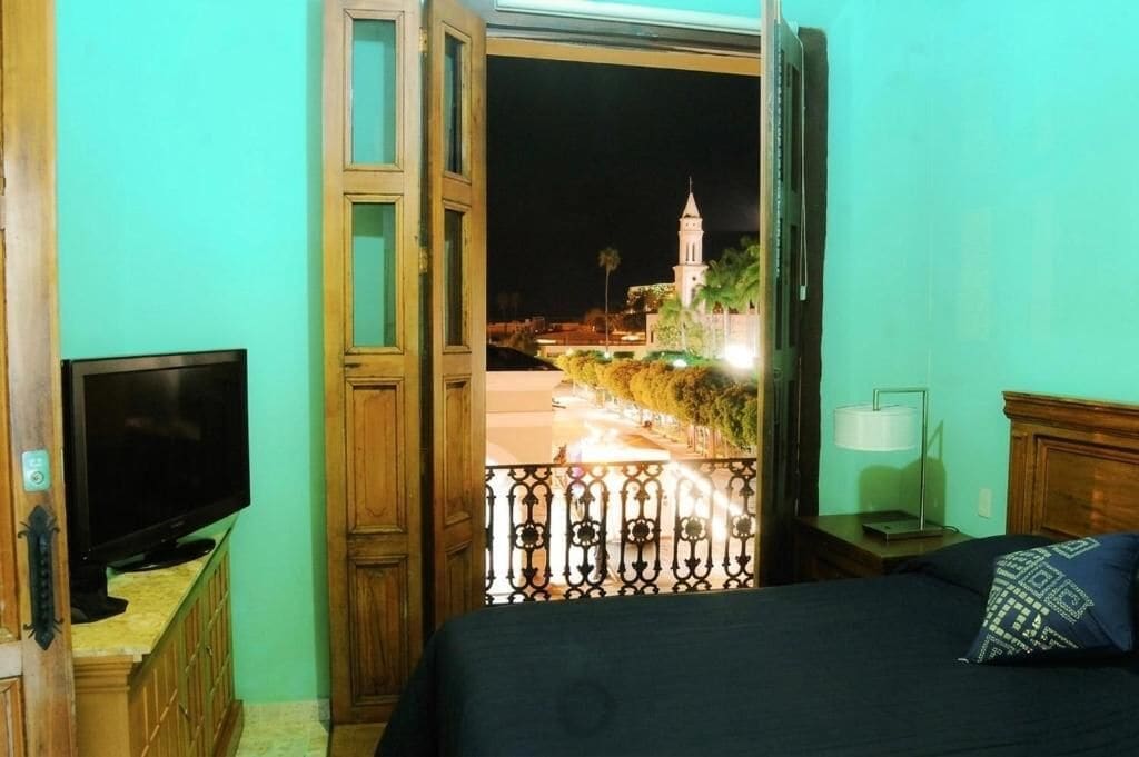 Una habitación con una cama, un televisor, una mesita de noche y vistas a un edificio iluminado de noche.
