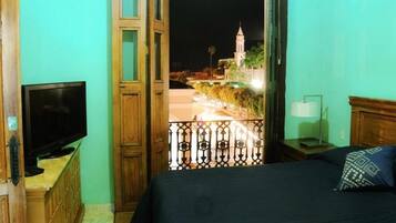 Una habitación con una cama, un televisor, una mesita de noche y vistas a un edificio iluminado de noche.