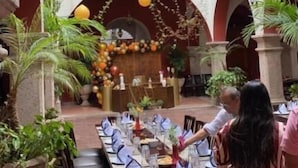 Un área de comedor al aire libre con mesas dispuestas para los huéspedes, rodeada de arcos y plantas en macetas.