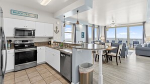 Een moderne keuken met roestvrijstalen apparatuur, een eetgedeelte met uitzicht en een woonkamer met uitzicht.