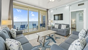 Een ruime woonkamer met een balkon, een plafondventilator en een flatscreen televisie.