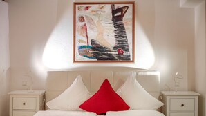 A bedroom with a bed, two bedside tables, a nightstand, a painting, and a window. - Edelzimmer Rothenburg (Rothenburg ob der Tauber)
