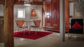 A dining area with a wooden table, four chairs, a red rug, and a large wooden cabinet. - Edelzimmer Rothenburg (Rothenburg ob der Tauber)