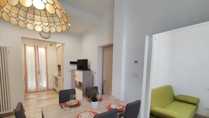 A dining area with a wooden table set for four, chairs, and a green sofa. - Lovely apartment for 5 people with WIFI, TV, terrace and pets allowed (Dongo)