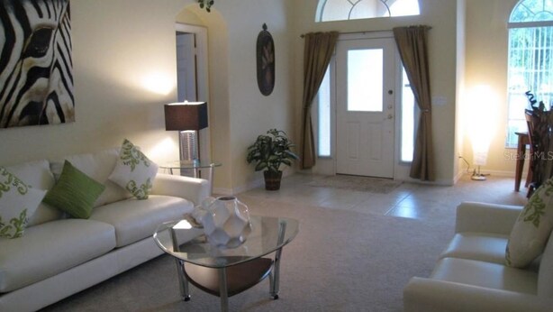 Ein Wohnzimmer mit einem weißen Sofa, einem Glastisch und einer Blumentopf-Pflanze.