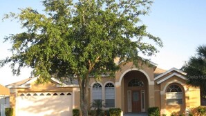 Ein Wohnhaus mit Garage, Rasen und Baum.