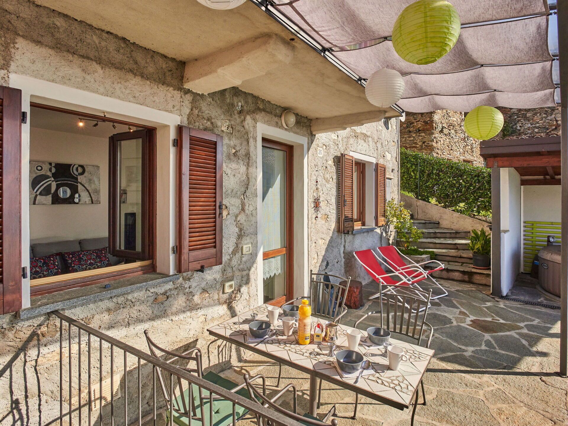 Ein Steinhaus mit einer Terrasse, ausgestattet mit einem Esstisch, Sitzgelegenheiten im Freien und einem Grill.
