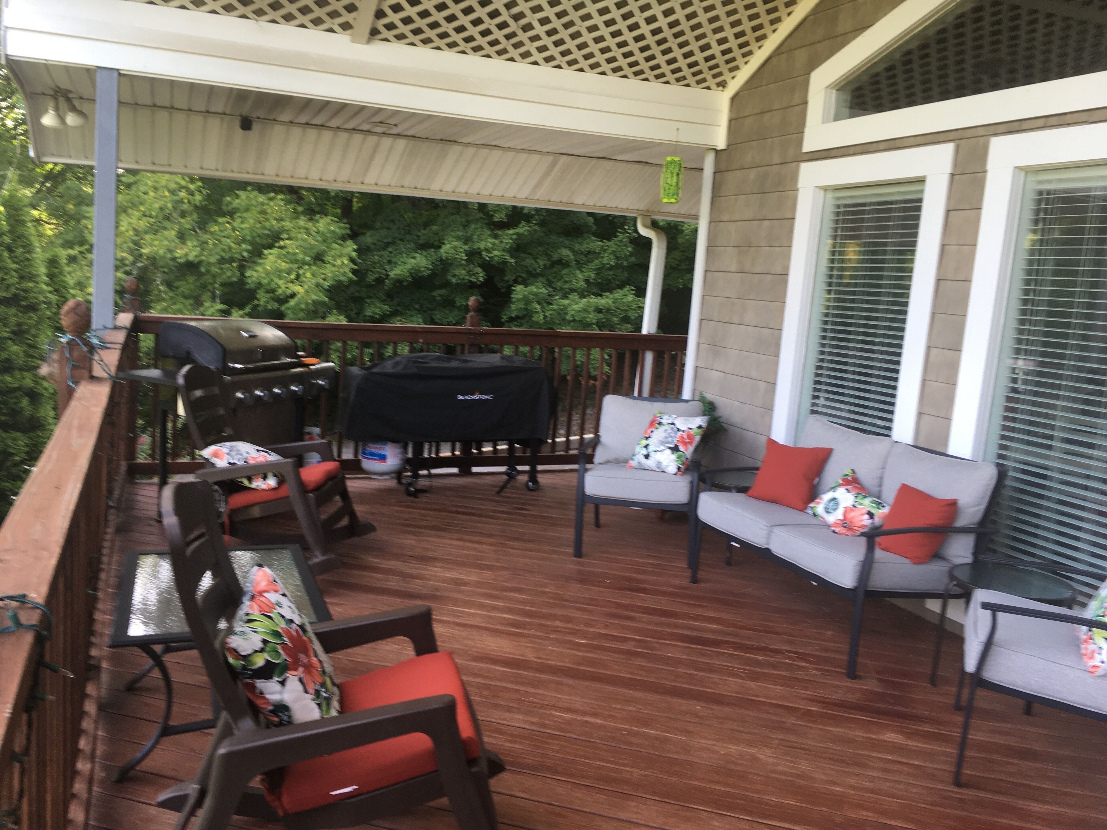 A covered outdoor deck with a grill, chairs, and a sofa.