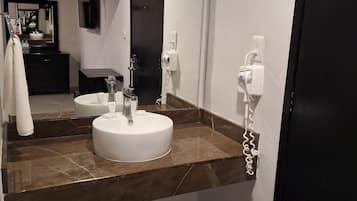 A modern bathroom with a white sink, a mirror, and a towel rack.