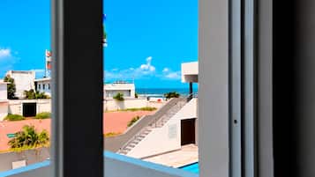 Vista desde una ventana con vista a una piscina, una escalera y un cielo azul despejado.