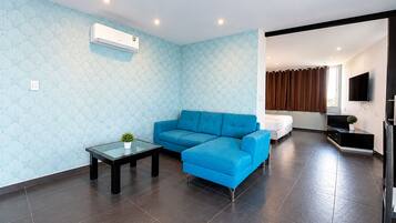 Ein modernes Wohnzimmer mit einem blauen Sofa, einem Glastisch und einem an der Wand befestigten Flachbildfernseher.