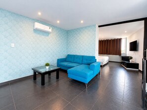 Una sala de estar moderna con un sofá azul, una mesa de centro de vidrio y un televisor de pantalla plana montado en la pared.