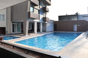Una piscina al aire libre, sillones reclinables de piscina