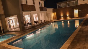 A swimming pool with a tiled deck, surrounded by a building with multiple windows and doors. - Hotel Costa Verde (Veracruz)