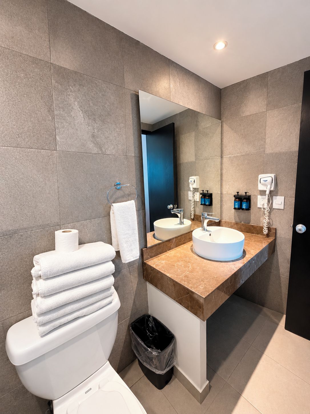 A modern bathroom with a toilet, sink, and mirror.
