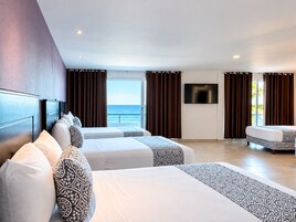 Habitación de hotel con dos camas, televisión y vista al mar.