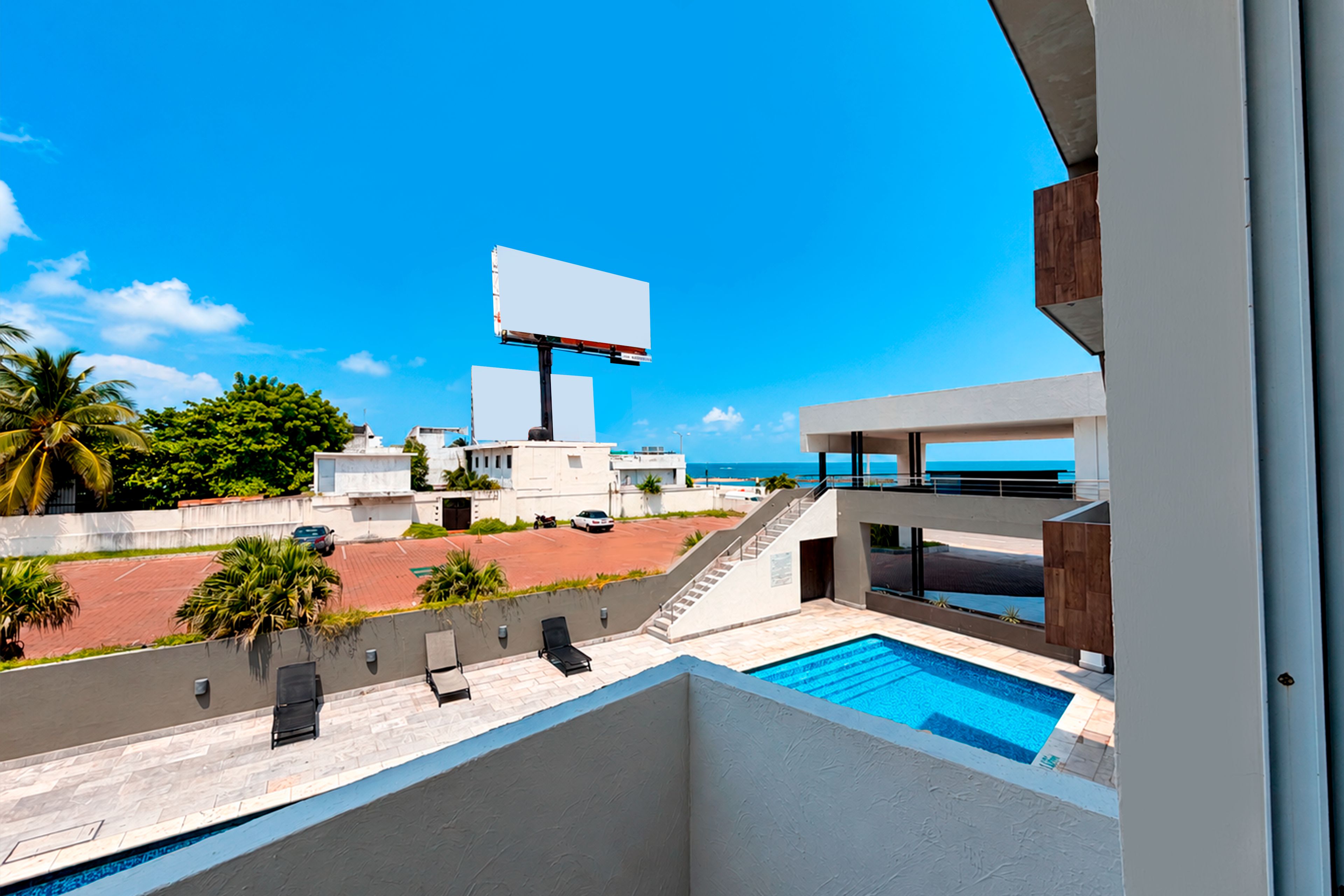 Un área de piscina moderna con vista despejada al océano y un gran cartel publicitario al fondo.