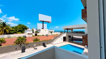 Un área de piscina moderna con vista despejada al océano y un gran cartel publicitario al fondo.