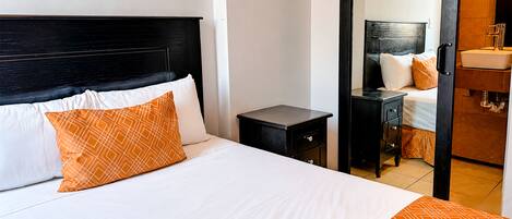 Habitación de hotel con cama, mesita de noche, cómoda y espejo.