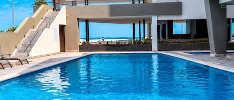 Un edificio moderno con piscina, escaleras exteriores y vista despejada al océano.