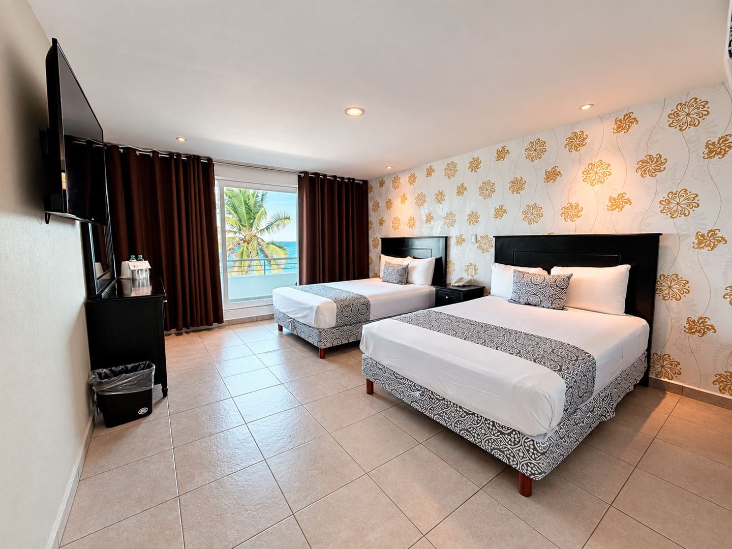 Une chambre d’hôtel avec deux lits, une télévision, un minibar et une vue sur l’océan.