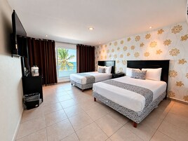 Une chambre d’hôtel avec deux lits, une télévision, un minibar et une vue sur l’océan.
