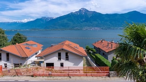 A coastal village with red-roofed houses, a clear view of the lake, and mountains in the background. - Beautiful apartment for 9 guests with hot tub, WIFI, TV, patio and pets allowed (Aurogna)