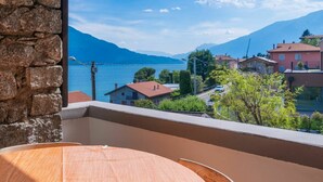A balcony with a view of a lake, mountains, and residential buildings. - Beautiful apartment for 9 guests with hot tub, WIFI, TV, patio and pets allowed (Aurogna)
