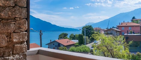 A balcony with a view of a lake, mountains, and residential buildings.