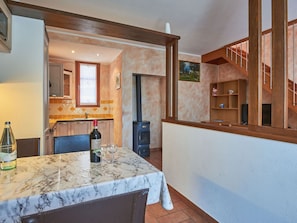 A dining area with a marble table, a bottle of wine, and a view of the kitchen and living area. - Stunning private villa for 5 people with WIFI, TV and terrace (Sorico)