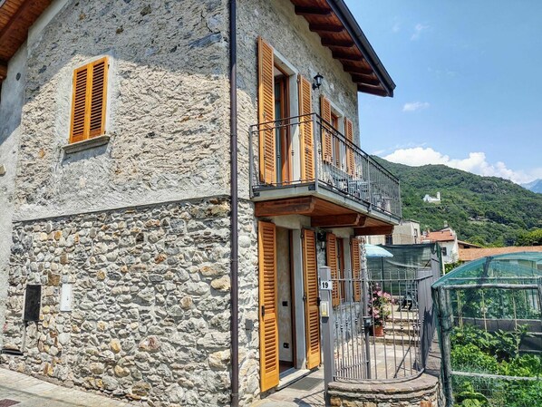 Un edificio de piedra con contraventanas de madera y un balcón.