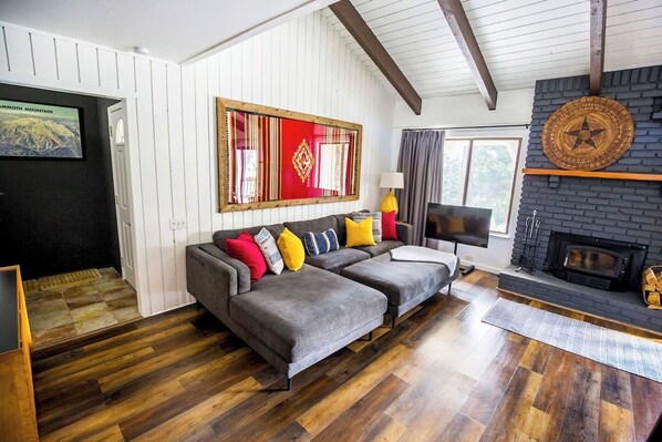 A living room with a grey sectional sofa, a fireplace, and a television.