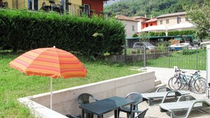 An outdoor patio with a table and chairs, a striped umbrella, and bicycles parked nearby. - Wonderful private villa for 3 people with pool, WIFI, A/C, TV, terrace and pets allowed (Sorico)
