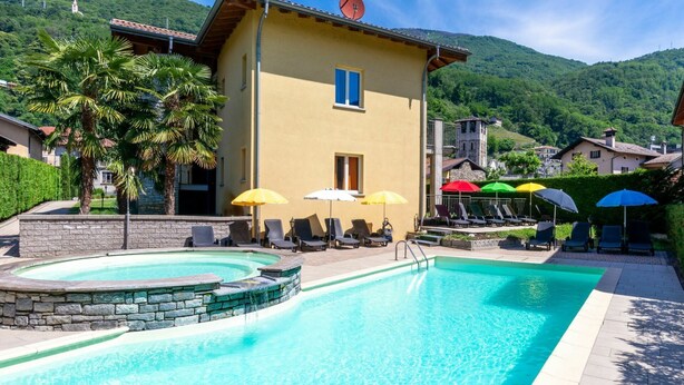 A pool area with lounge chairs and umbrellas, surrounded by a mountain landscape. - Wonderful private villa for 3 people with pool, WIFI, A/C, TV, terrace and pets allowed (Sorico)