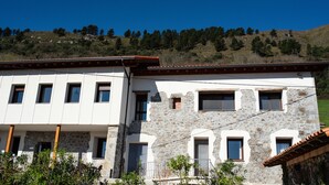 A two-story building with a stone facade and multiple windows. - Pico El Hayal - Apar located in a rural setting with 2 bedrooms, kitchen, living room and bathroom (Ampuero)
